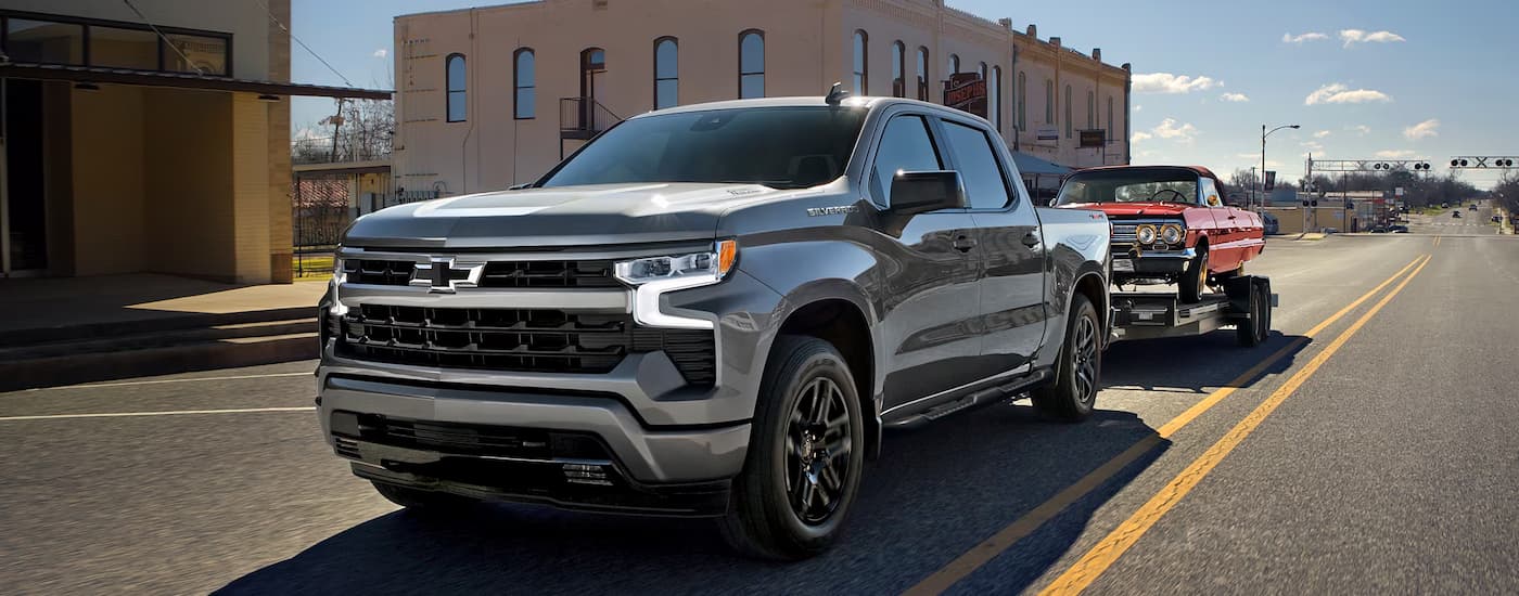 Grey 2026 Chevy Silverado 1500 towing a red car on a trailer
