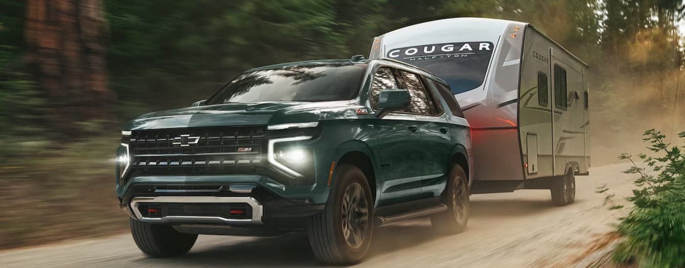 A green 2026 Chevy Tahoe towing a trailer.