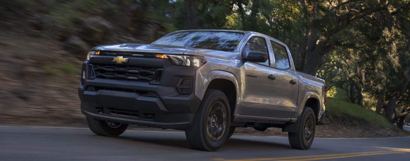 Grey 2026 Chevy Colorado driving on a paved road.