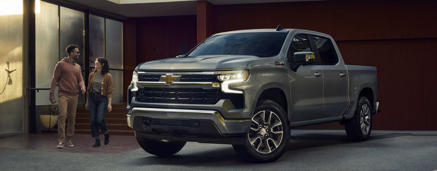 Grey 2026 Chevy Silverado 1500 parked in a driveway with a couple walking to it.