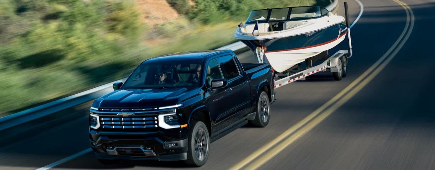 A black 2027 Chevy Silverado 1500 towing a boat.