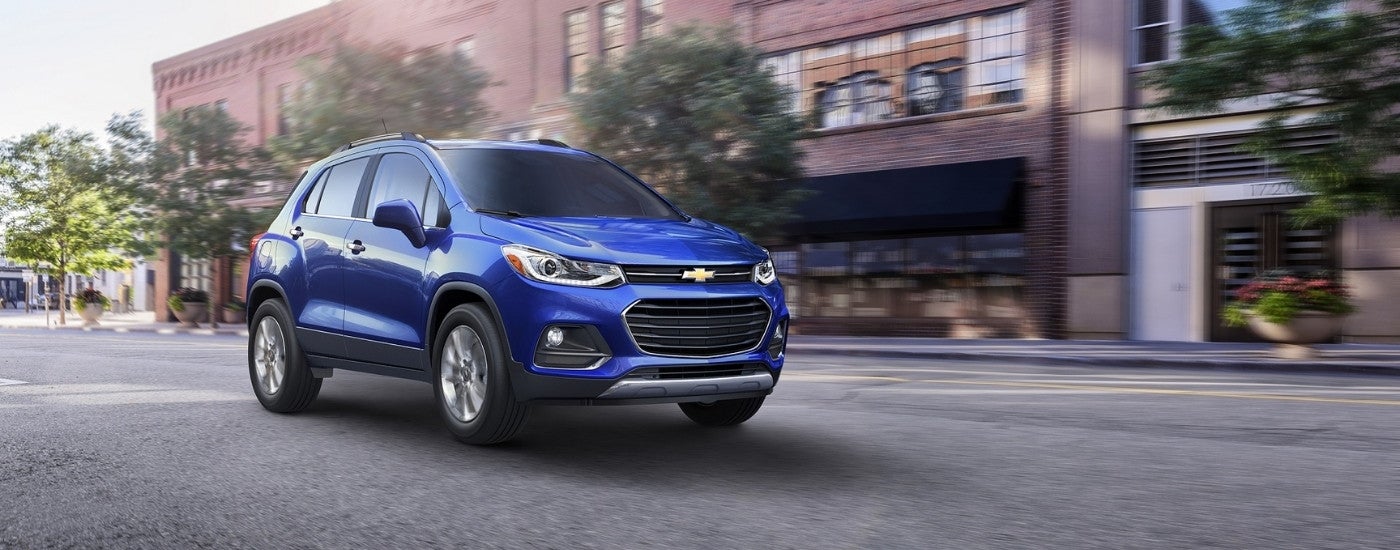 A blue 2017 Chevy Trax driving on a city street.