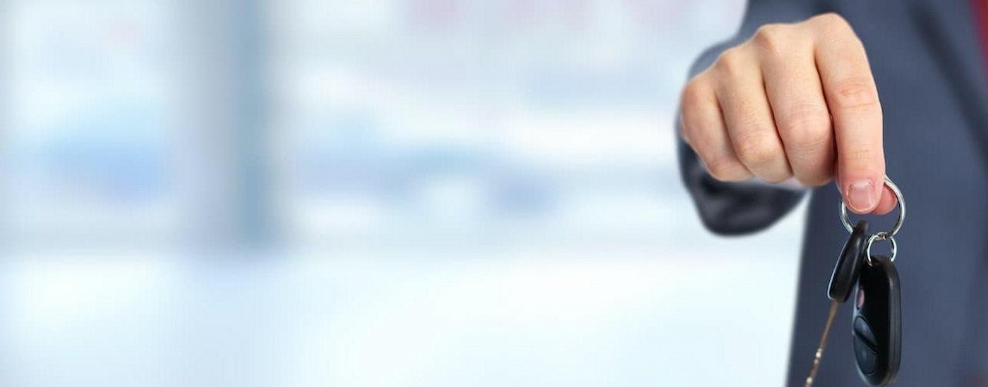 A person holding a key at Braun's Farm Chevy dealership.