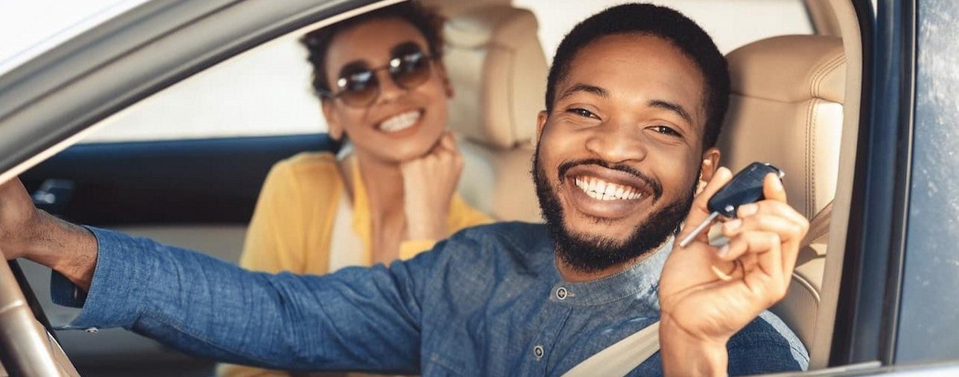 Two people smiling a vehicle.