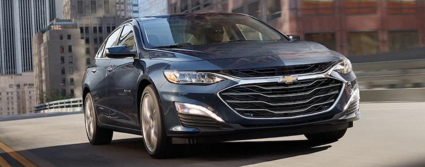 A blue 2020 Chevy Malibu driving from a Certified Pre-Owned Chevy dealer.