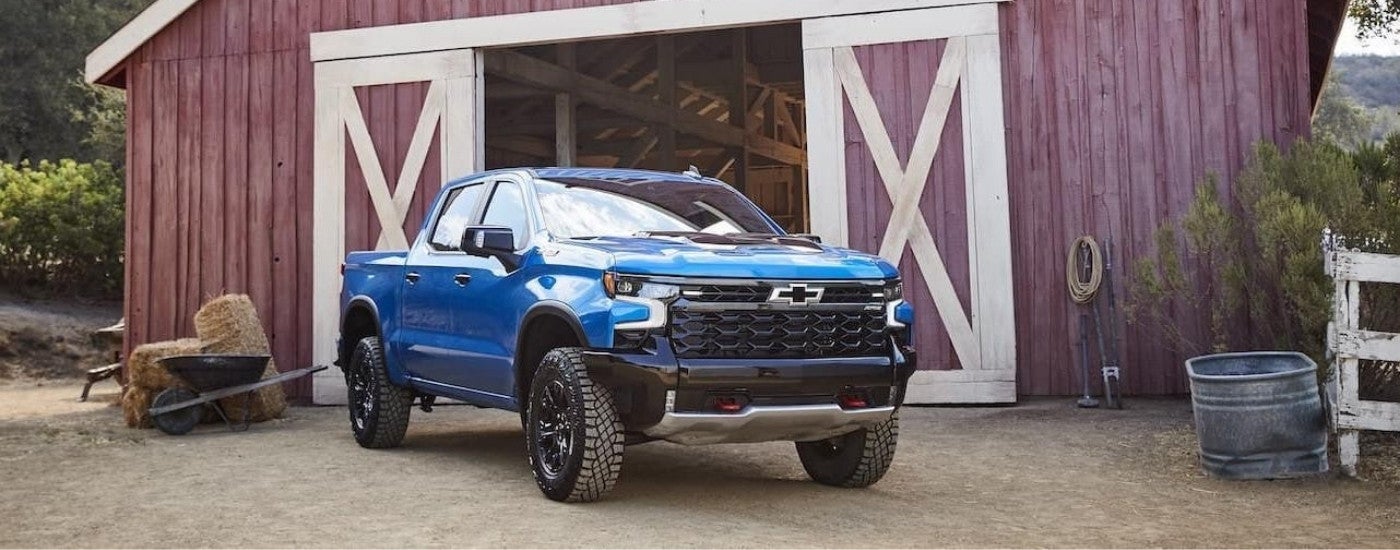 A blue 2022 Chevy Silverado 1500 ZR2 parked outside of a red barn.