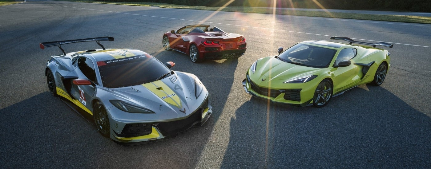 A silver, a red, and a yellow 2023 Chevy Corvette Z06 parked on the pavement at different angles on a sunny day.
