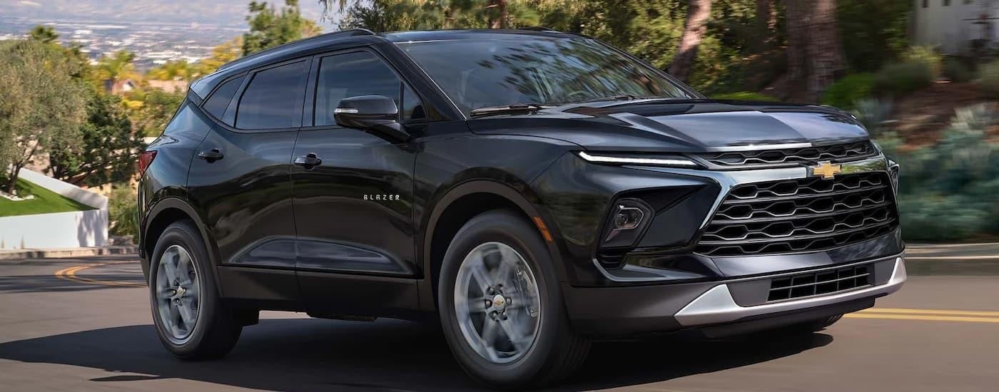 A black 2023 Chevy Blazer is driving on a winding street after leaving a Chevy dealer near Pearsall.