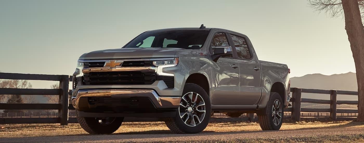 A silver 2024 Chevy Silverado 1500 LT Z71 is parked on a farm.
