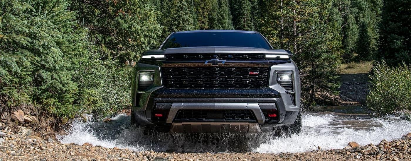 A silver 2024 Chevy Traverse Z71 is driving through a rocky river.
