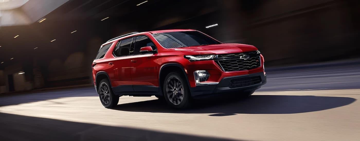 A red 2023 Chevy Traverse RS is shown driving on a city street after leaving a Boerne Chevy dealer.