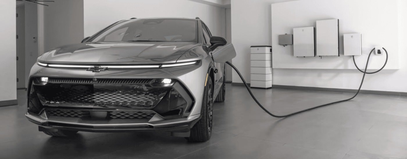 A silver 2025 Chevy Equinox EV RS is parking inside of a garage while charging.