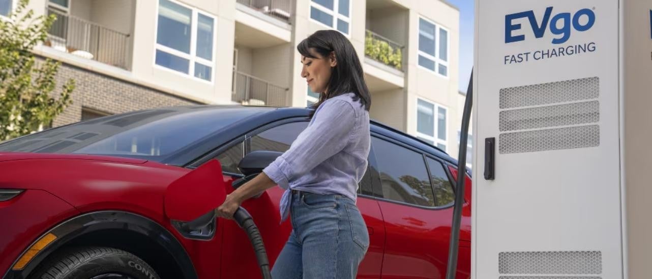 A person is shown charging a red 2025 Chevy Equinox EV.
