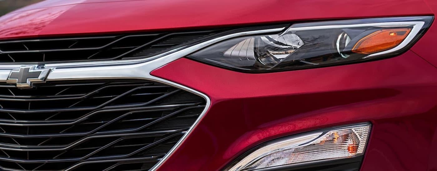 A close up of the grille on a red 2024 Chevy Malibu for sale.