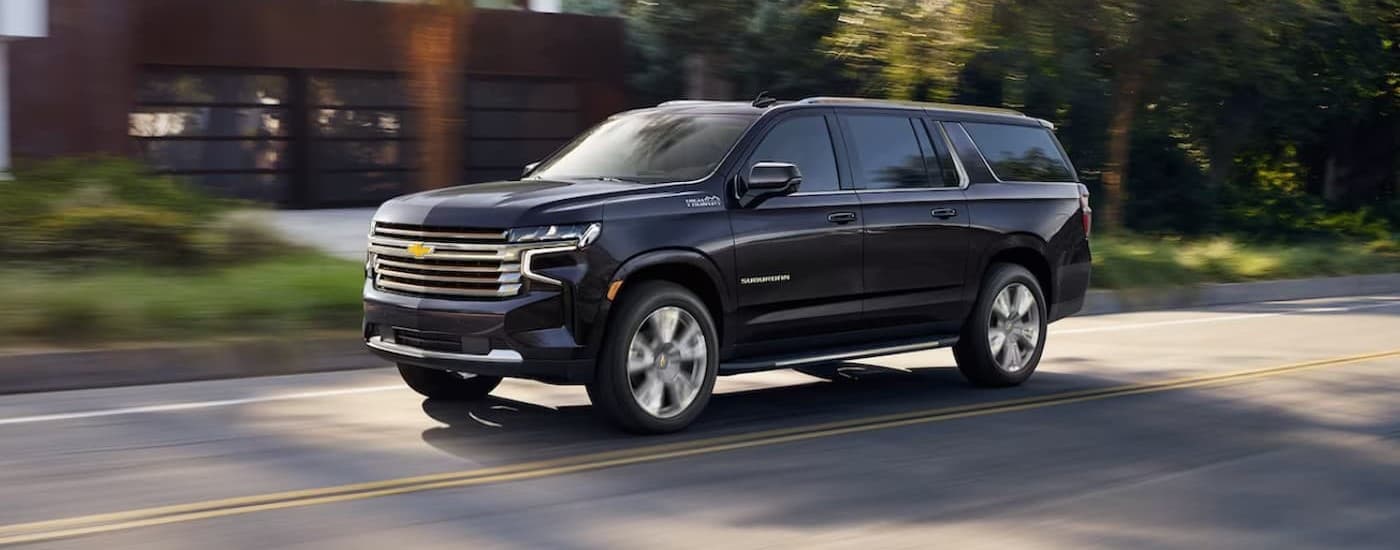 A blue 2026 Chevy Suburban driving in a city.