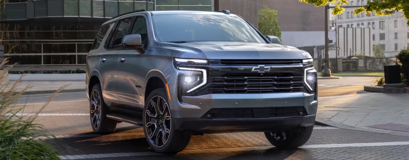 Silver 2025 Chevy Tahoe driving in a city.