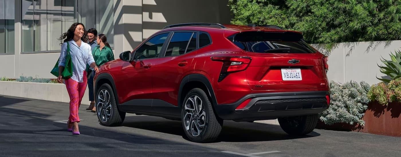 A red 2024 Chevy Trax RS is parked on the side of a city street.