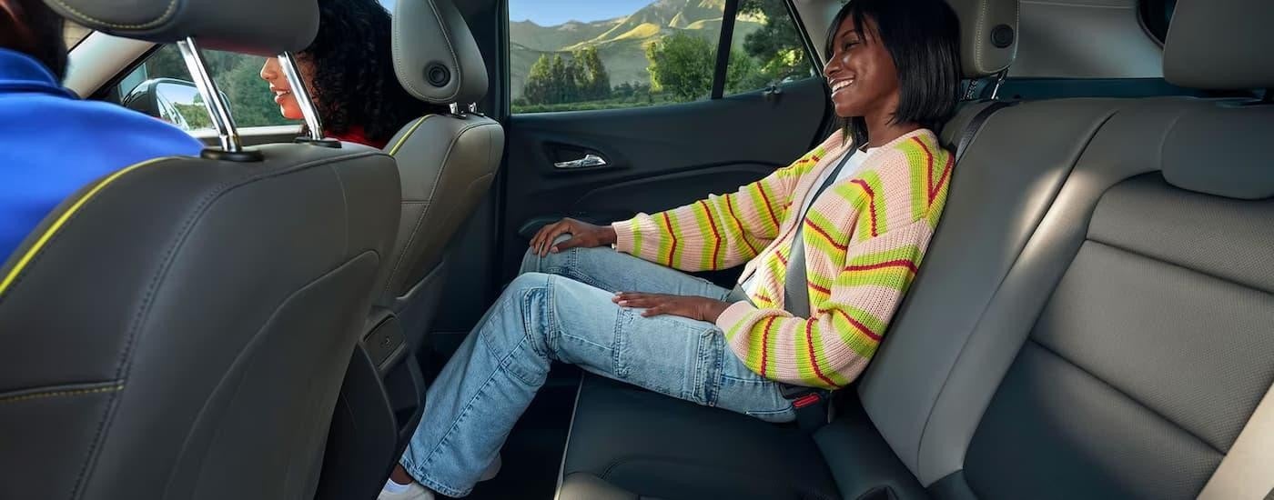 A woman is sitting in the backseat of a 2024 Chevy Trax for sale.
