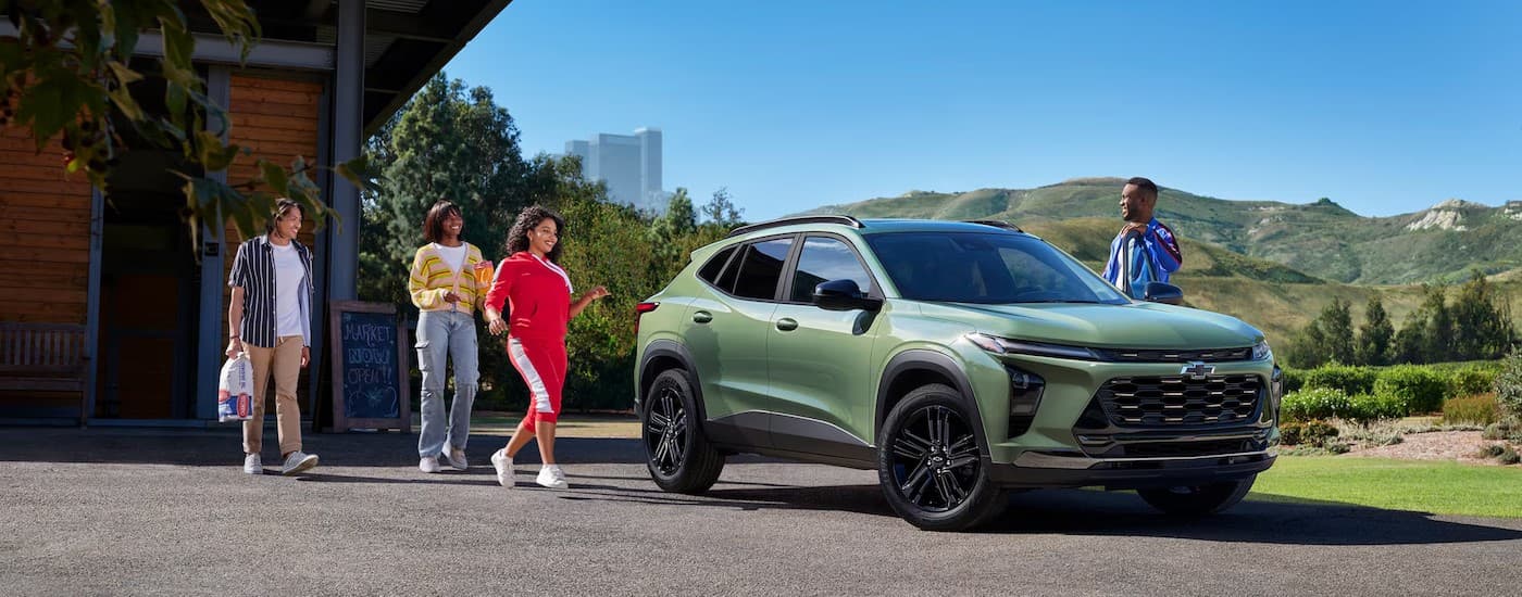 People walking towards a green 2025 Chevy Trax.