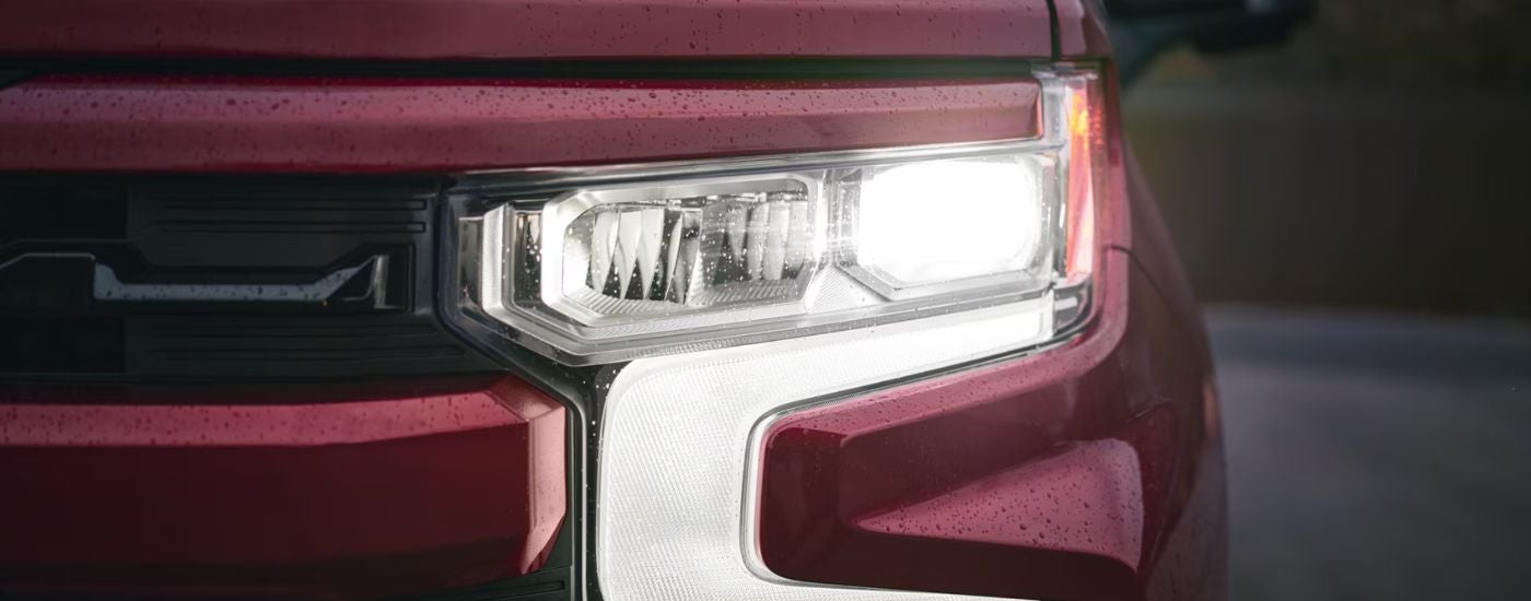 Close up of a headlight on a red 2026 Chevy Silverado 1500 RST.