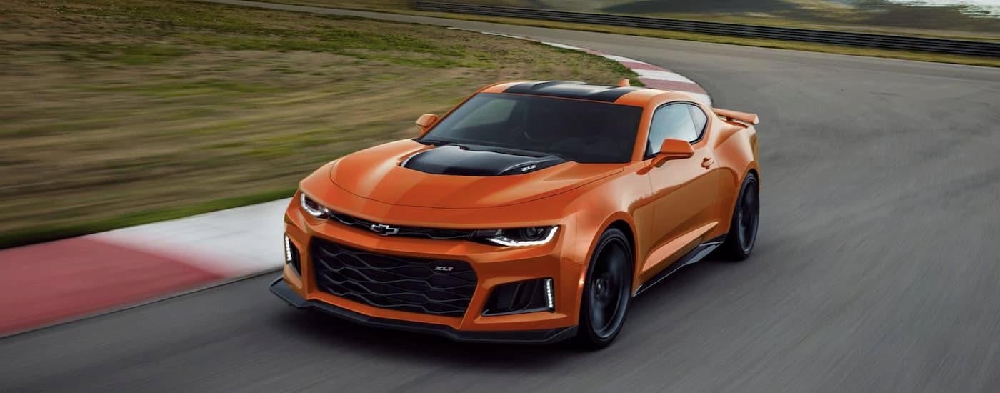 An orange 2022 Chevy Camaro driving on a race track after leaving a Devine Chevy dealer.