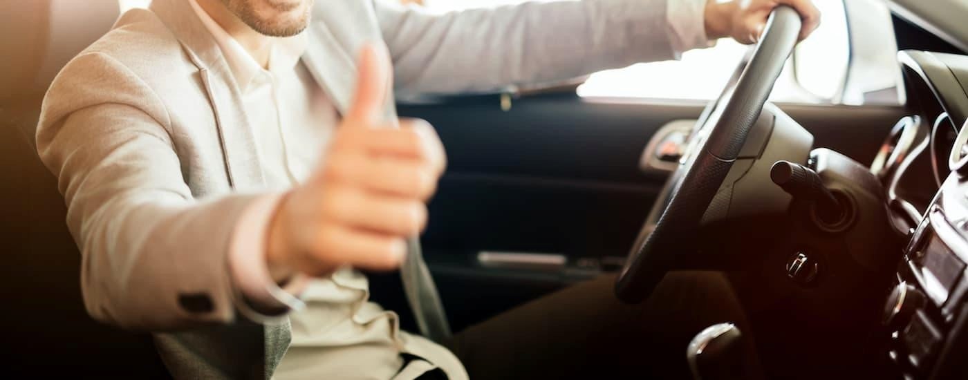 A person giving a thumbs up in a vehicle.