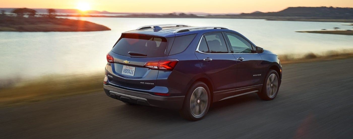 A blue 2022 Chevy Equinox is driving past a lake.