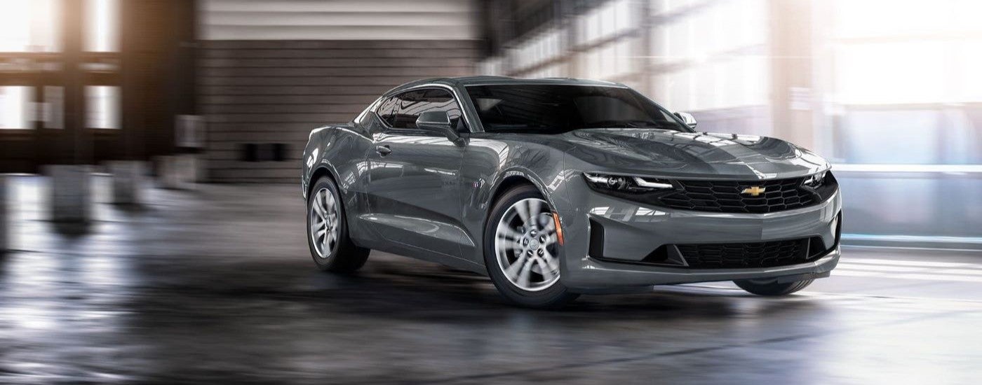 A grey 2022 Chevy Camaro is driving out of a parking garage.