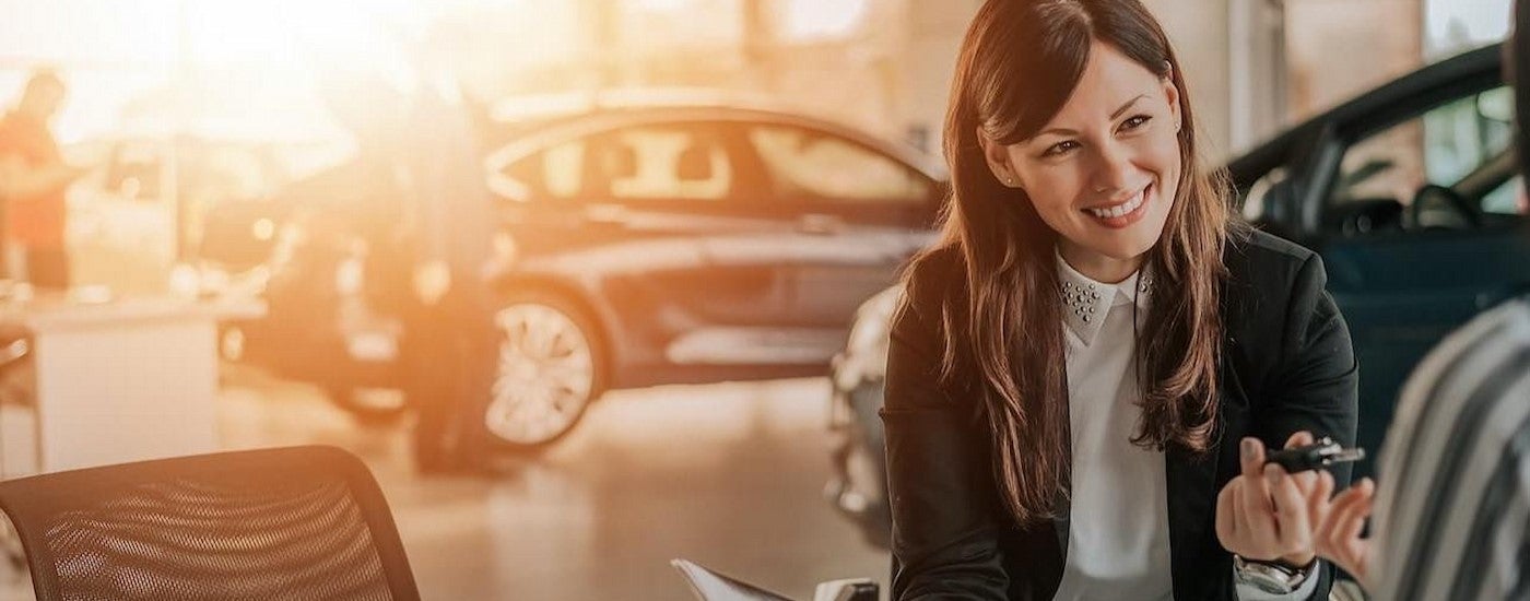 A person in a dealership holding a key.