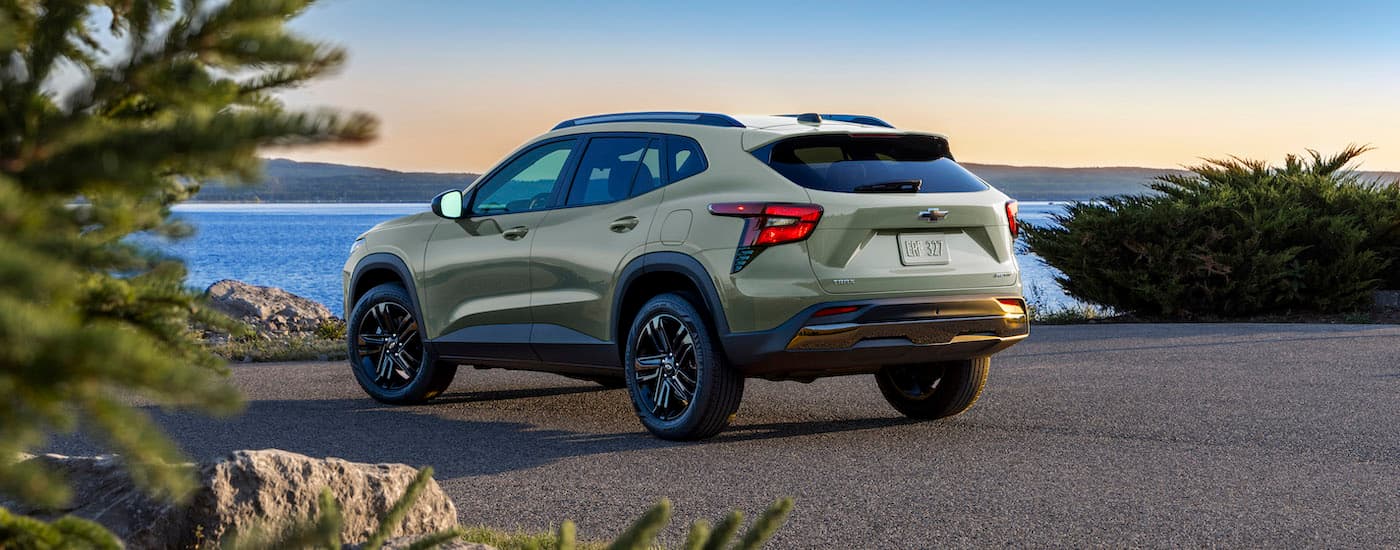 A popular SUV for sale, a green 2024 Chevy Trax ACTIV, parked near a lake.