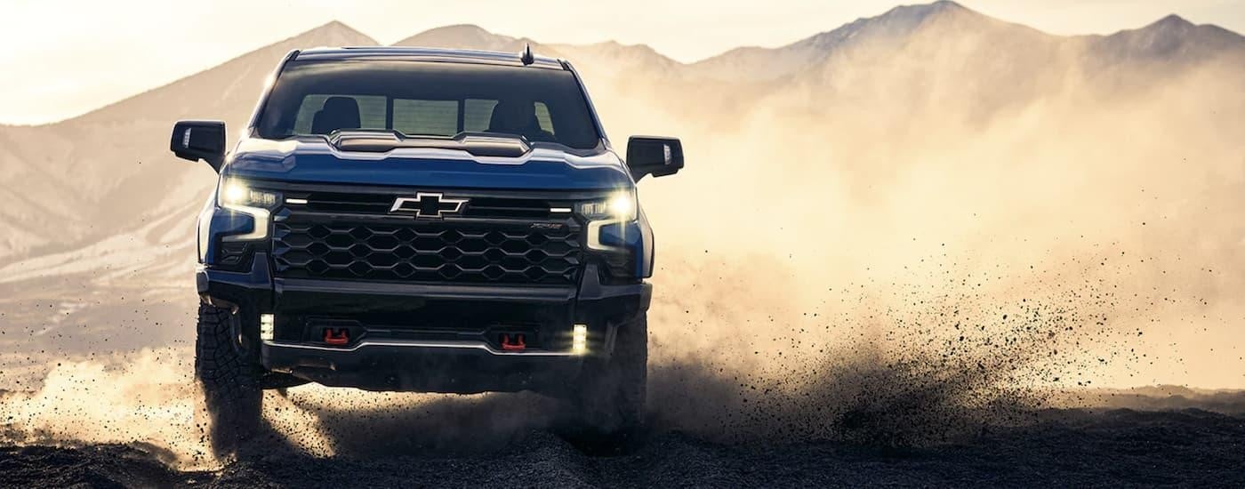 A blue 2022 Chevy Silverado 1500 ZR2 is shown from the front off-roading and kicking up dust.