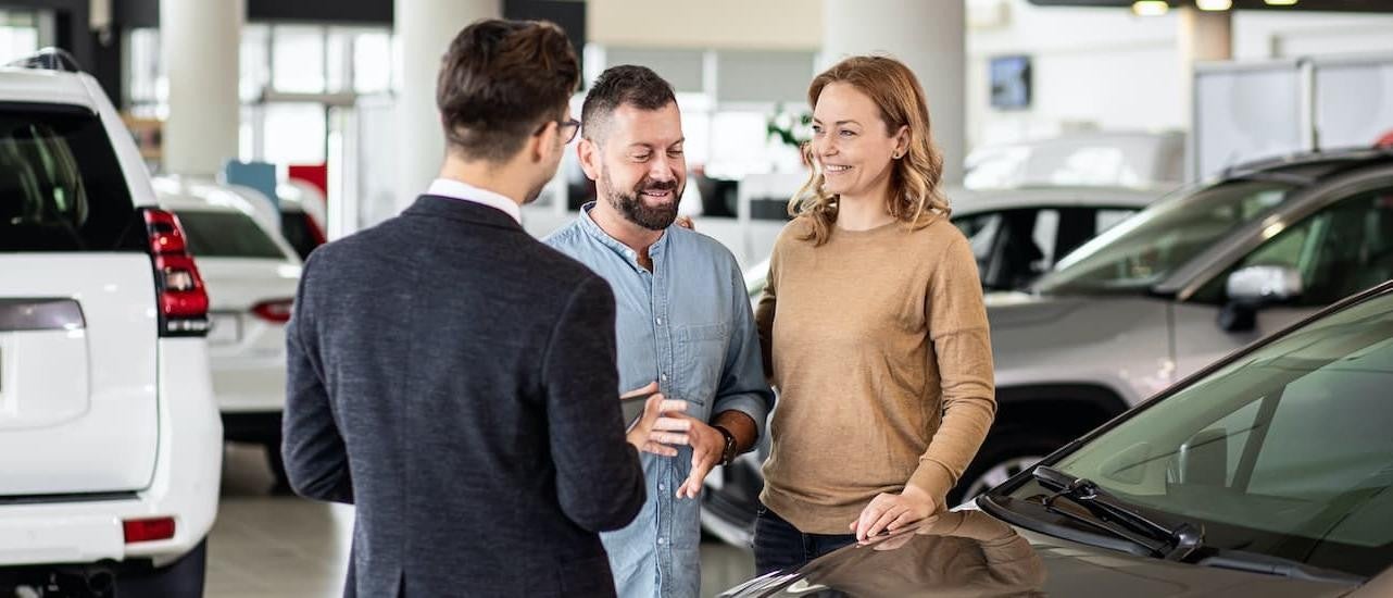 A couple is shown talking to a salesperson at a San Antonio used Chevy dealer.