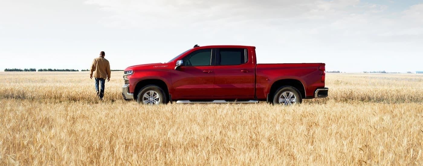 A red 2020 Chevy Silverado 1500 is shown from the side parked in a field after leaving a San Antonio used Chevy dealer.