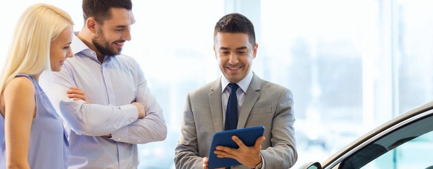 Three people talking in a dealership.