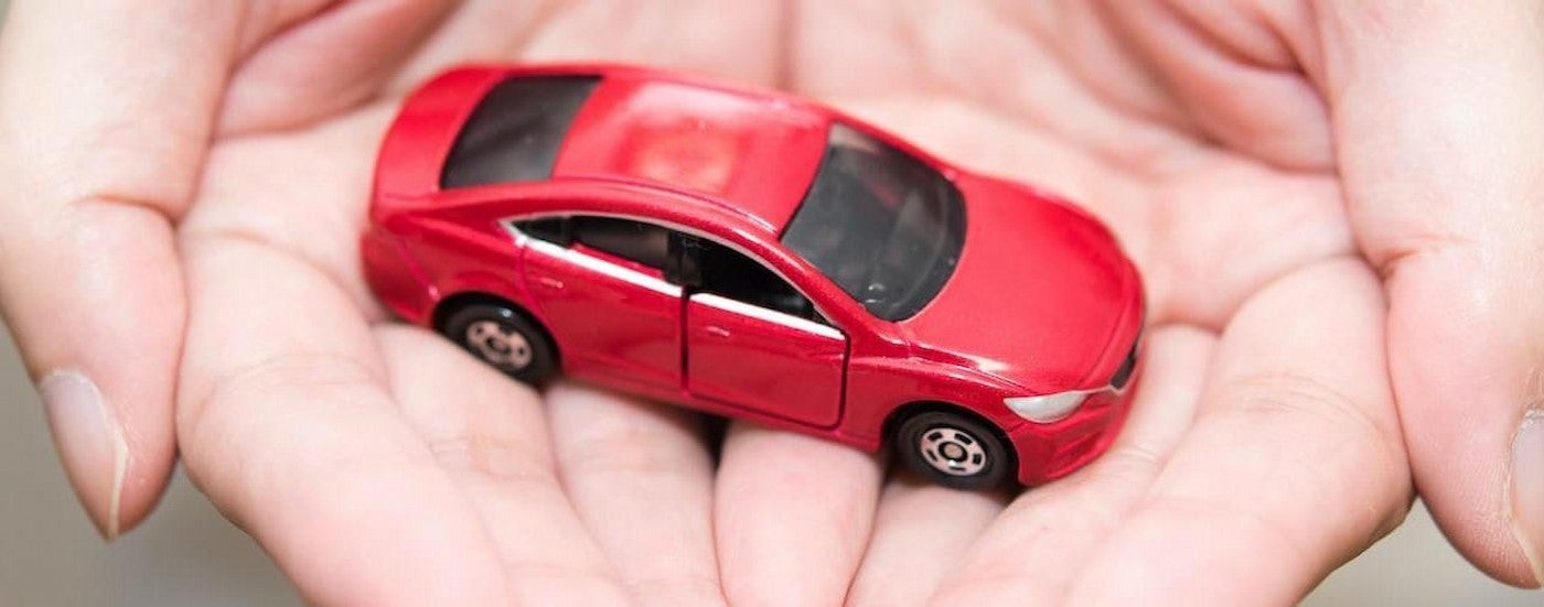 A red toy car in hands.
