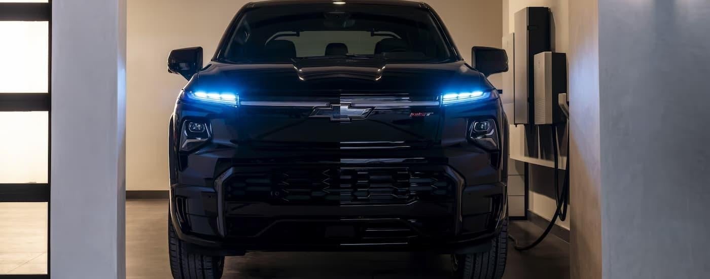 A black 2025 Chevy Silverado EV is parked in a garage and charging.