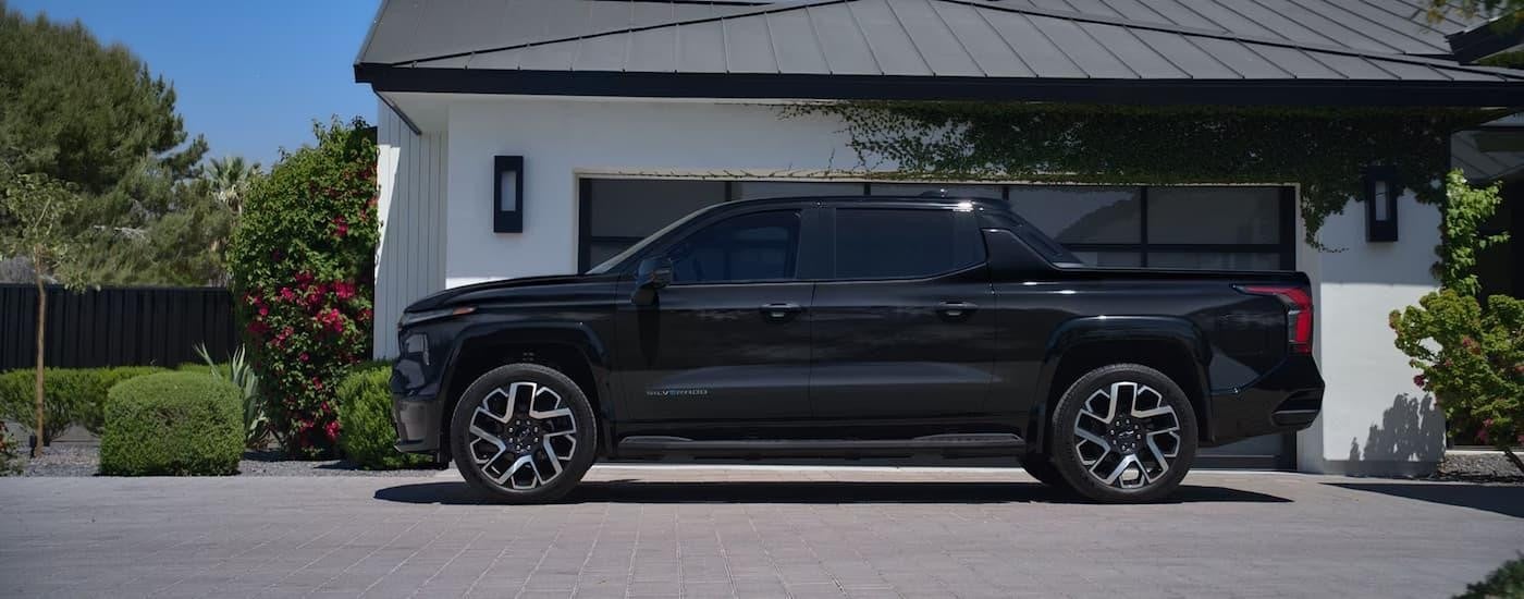 A side view of a black 2025 Chevy Silverado EV parked in a driveway.