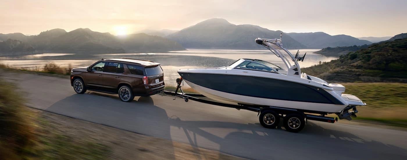 A brown 2023 Chevy Tahoe towing a boat.