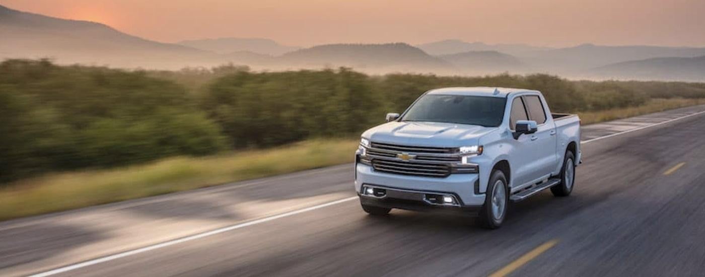 A white 2021 Chevy Silverado 1500 High Country driving on an open road.