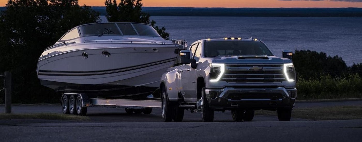 A white 2024 Chevy Silverado 3500HD LTZ towing a boat