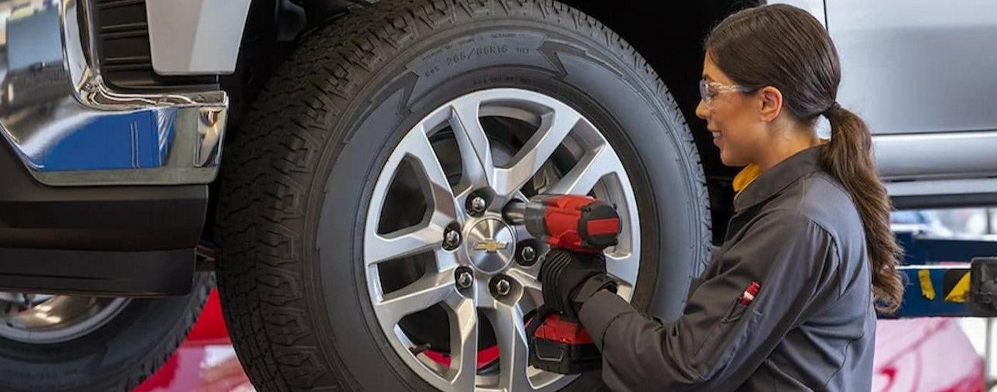 A mechanic removing a wheel at a used truck dealership.
