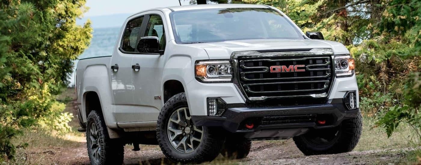 A white 2022 GMC Canyon is shown from the front off-roading.