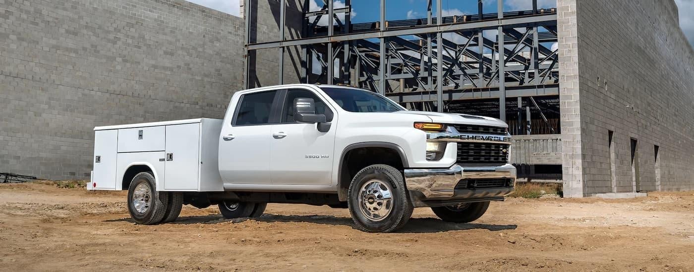 A white 2023 Chevy Silverado 3500HD Chassis is shown parked at a construction site.