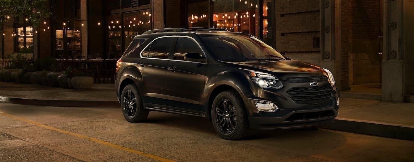 A black 2017 Chevy Equinox Midnight parked in front of a building at night.