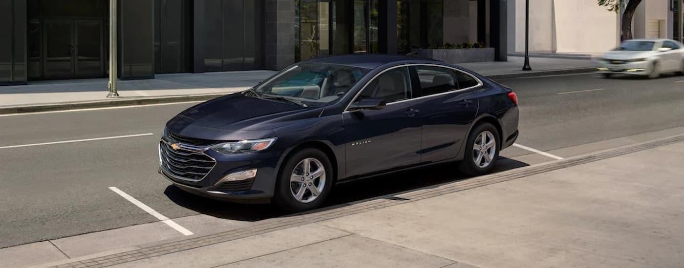 A popular budget car for sale, a blue 2022 Chevy Malibu, is shown parked on the side of a street.