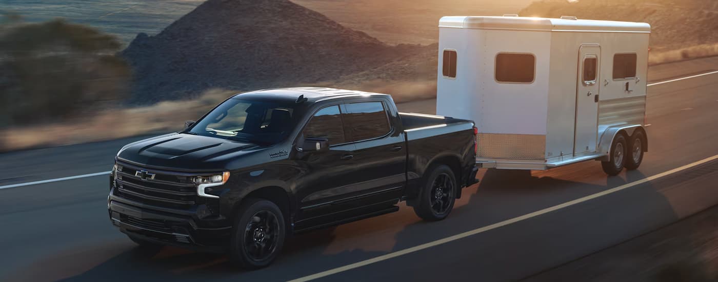 A black 2026 Chevy Silverado 1500 towing a horse trailer behind