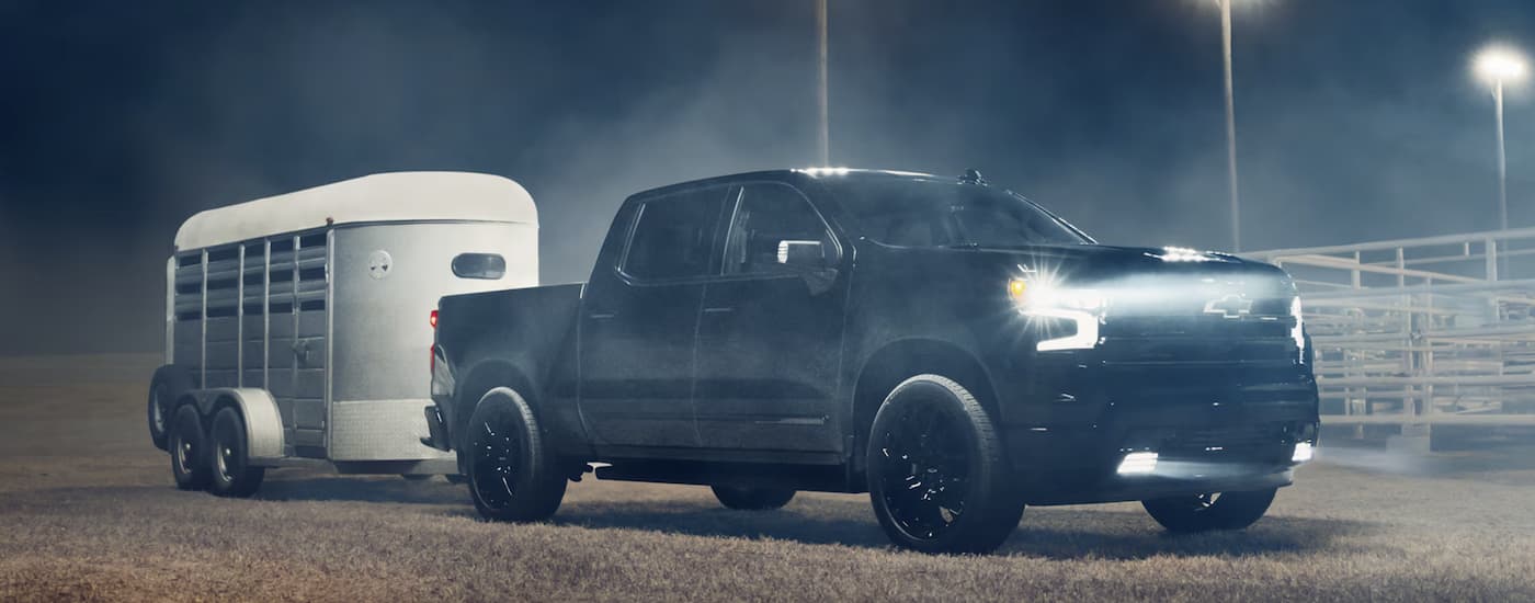 A black 2026 Chevy Silverado 1500 towing a horse trailer
